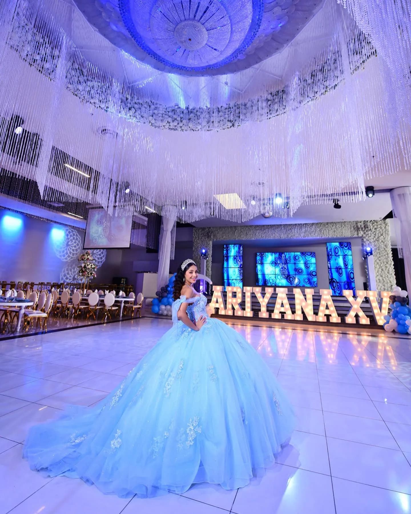 Quinceañera in a blue gown on the Legends Event Center ballroom floor